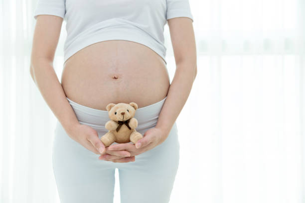 istock Pregnant woman holding a small teddy bear 908314844