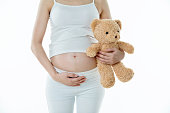 Pregnant woman holding a big teddy bear