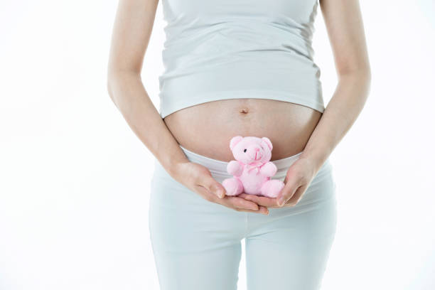 istock Pregnant woman holding a small teddy bear 908317102