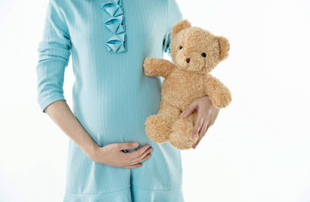 istock Pregnant woman holding a teddy bear 908317244