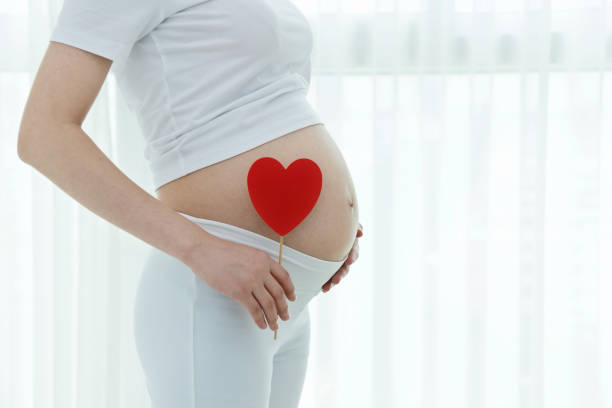 istock Pregnant women hand holding a heart shape 908318020