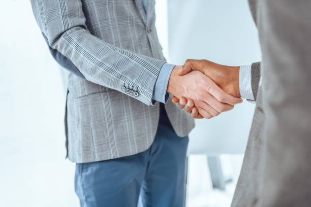 istock cropped image of two businessmen shaking hands at office space 908323816