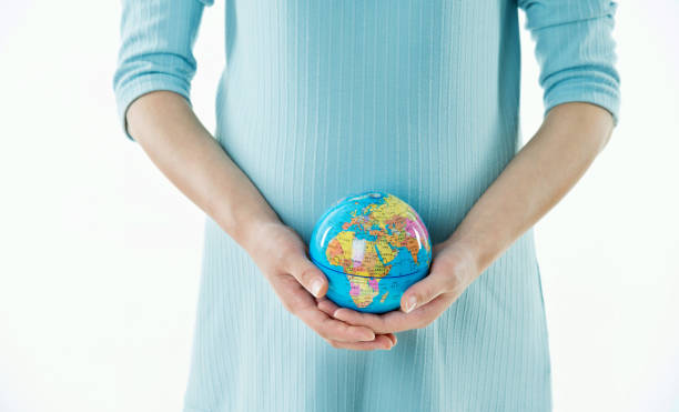 istock Pregnant woman holding a globe 908327218