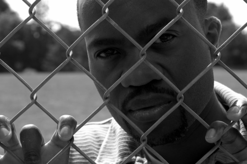 African American male behind a fence.