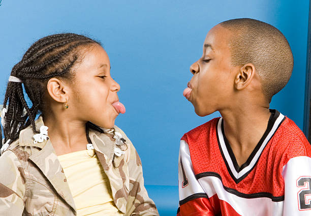 A kissing teenage couple photographed with blue sky and clouds in the background