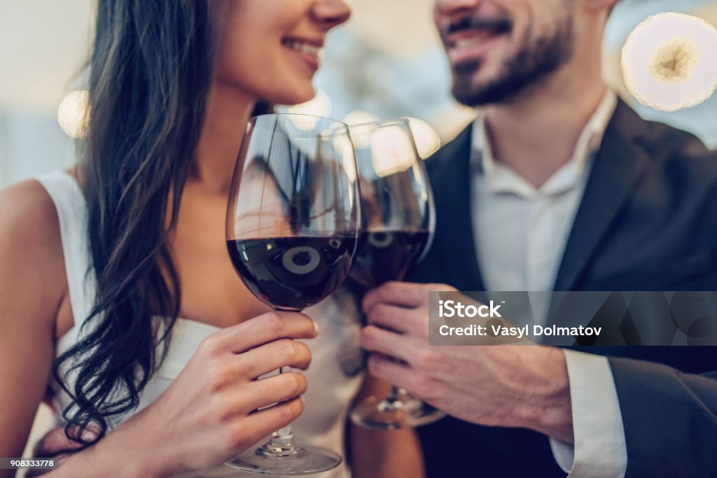 Romantic couple in restaurant Cropped image of loving couple is spending time together in modern restaurant. Attractive young woman in dress and handsome man in suit are having romantic dinner. Celebrating Saint Valentine's Day. Couple - Relationship Stock Photo