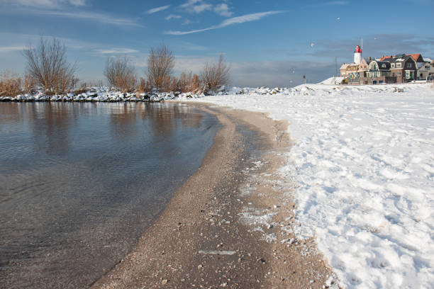 istock Dutch beach covered with snow and view at lighthouse Urk 908344318