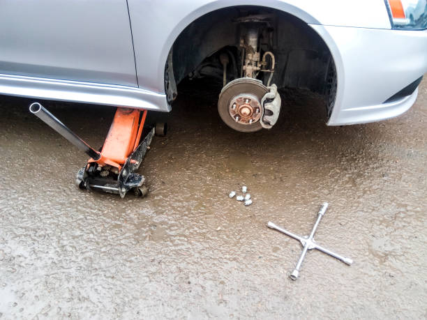 la voiture est à la boutique de pneu. en vertu de la prise de la voiture dans le centre de l’entretien de la voiture. la voiture avec la roue enlevée. - garage sale flash photos et images de collection