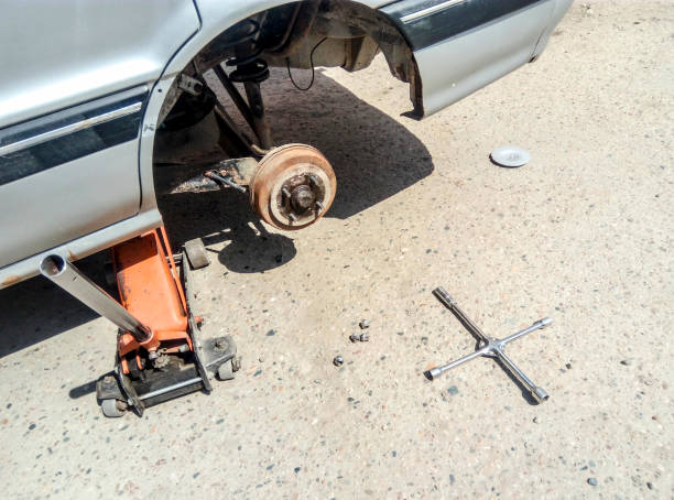 la voiture est à la boutique de pneu. en vertu de la prise de la voiture dans le centre de l’entretien de la voiture. la voiture avec la roue enlevée. - garage sale flash photos et images de collection