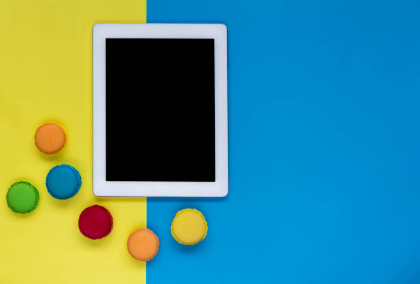 istock Digital Tablet with colorful macaroons on color block background 908353142
