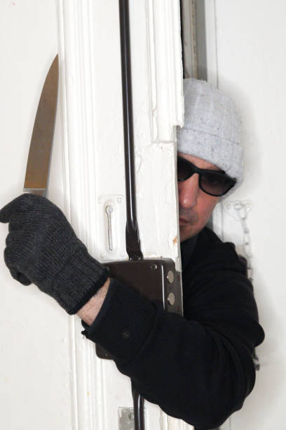 istock Robber armed with a knife peeping out of a door 908353172