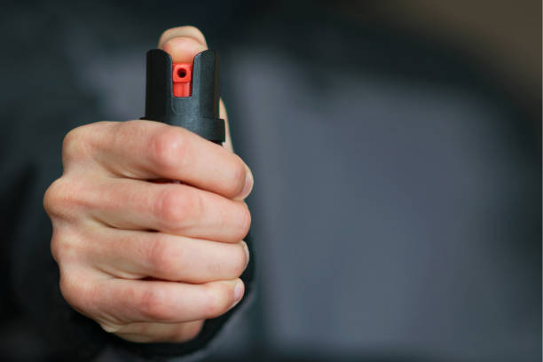 istock Man holding pepper spray (tear gas) in his hand. Self-defense. Blur background, close up 908356562