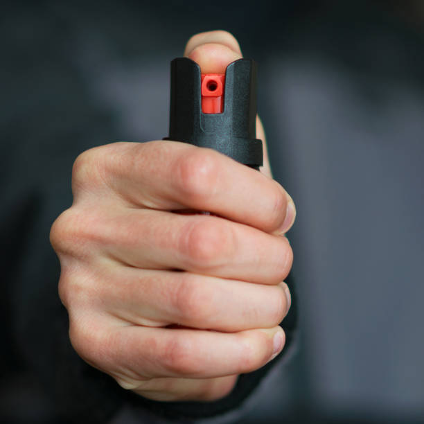 istock Man holding pepper spray (tear gas) in his hand. Self-defense. Blur background, square, close up 908356564