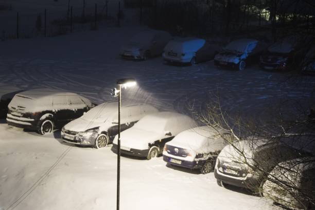 istock Cars covered by snow at night during snowfall in winter. 908356848