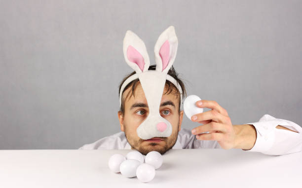 tired man in the mask Easter Bunny looking at the egg, after party