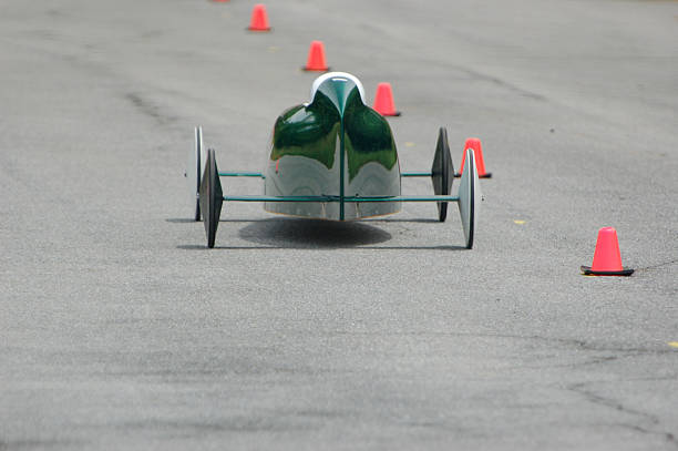 Green Race Car Green gravity powered soap box car speeds down a hill. Wheels are white and black because racers trade two wheels between heats so that races are decided by skill rather than better equipment. soapbox cart stock pictures, royalty-free photos & images