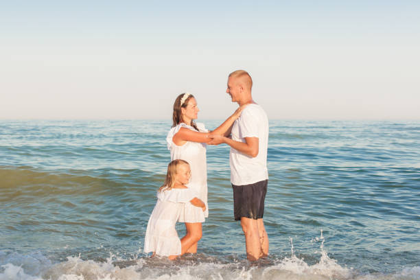 istock Dad, mom and daughter are standing on the beach. 908376422