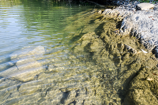 The mountain river. Shallow mountain river, water flows through the rocks. Rocks in the river water. Stones and layers of sedimentary rocks