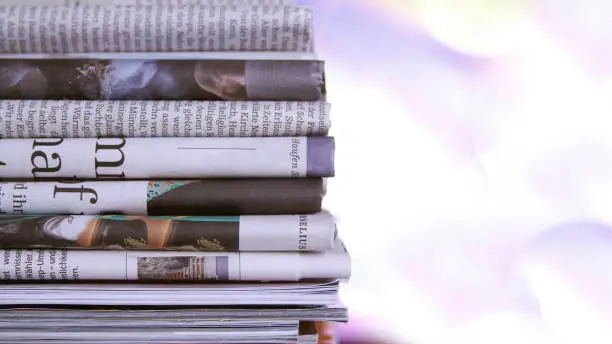 Some newspaper, stacked on bokeh background