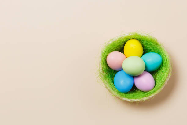 istock Six colorful pastel monophonic painted Easter eggs in basket with green grass isolated on beige background. Happy Easter concept. Copy space for advertisement. With place for text. Top view on eggs. 908398342
