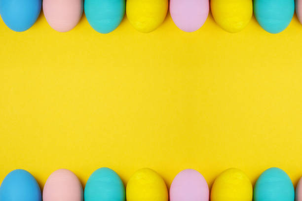 istock Double row colorful pastel monophonic painted Easter eggs isolated on yellow background for card or postcard. Happy Easter concept. Copy space for advertisement. With place for text. Top view on eggs. 908398568