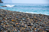 Pebble stones by the sea. Silky waves of blue sea