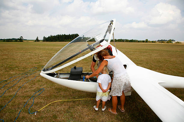 Girl in a yellow panama hat launches a toy plane into the field. Summer time, childhood, dreams and carelessness. Air tour from a travel agency on a trip, adventure and vacation. Village, cottage core