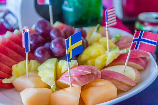 Fresh chopped and chunks fruits with flags on dish served in the restaurant.
