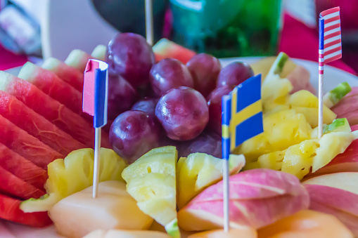 Fresh chopped and chunks fruits with flags on dish served in the restaurant.