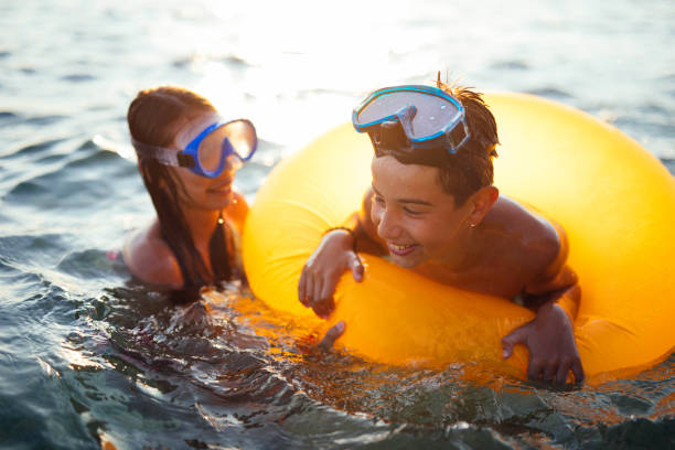 istock Friends playing in sea on sunset 908430652