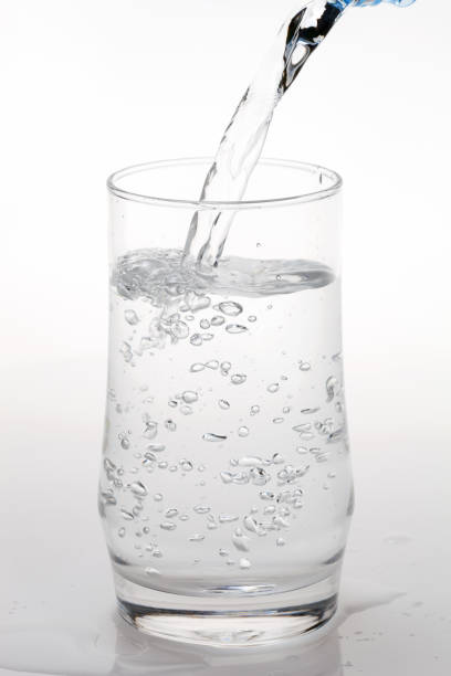 istock pouring water on a glass on white background. 908450856