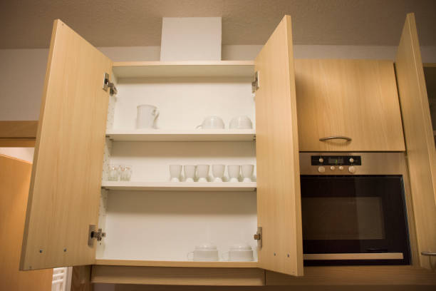 Blurred kitchen background and white cupboard with wooden shutter doors. Stylish cabinet with louver slats. Cozy home scene and atmosphere hygge. Warm light.