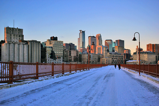 Beautiful winter morning in Minneapolis. Downtown cityscape from the Stone Arch Bridge on a skyline and skyscrapers in the rising sun light. Minnesota state, Midwest USA.