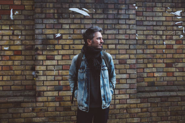 istock Young man in central London, standing against the brick wall 908468292