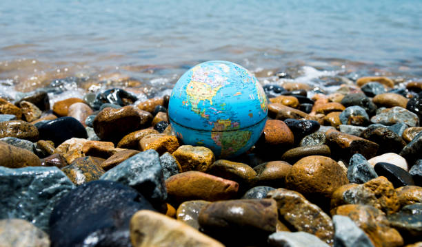 istock Globe earth on top of pebbles 908468828