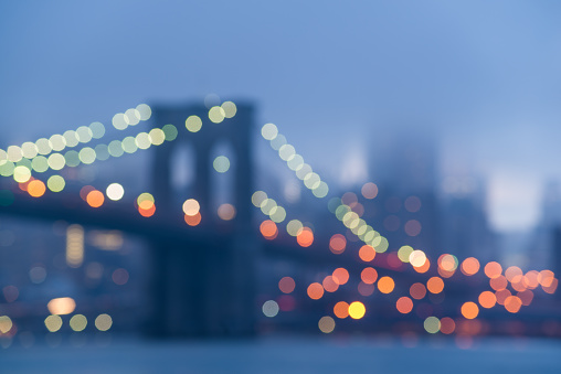 Abstract bokeh view of the Brooklyn Bridge on a foggy evening.