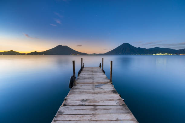 Sunrise Lake Atitlán A view looking down a wharf on Lake Atitlán at sunrise. dormant volcano stock pictures, royalty-free photos & images