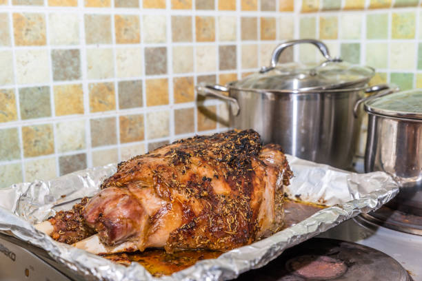 istock Closeup cooked lamb leg joint on roasting tin foil ready for serving 908505910