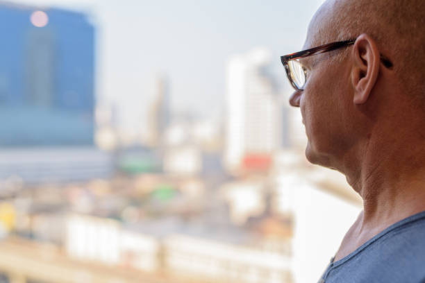 istock Rear View Of Senior Man Looking Through Window 908518778