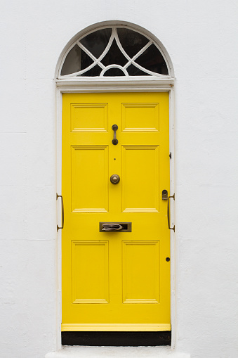 front view of yellow elegant residential apartment door with glass window and metallic vintage mailbox