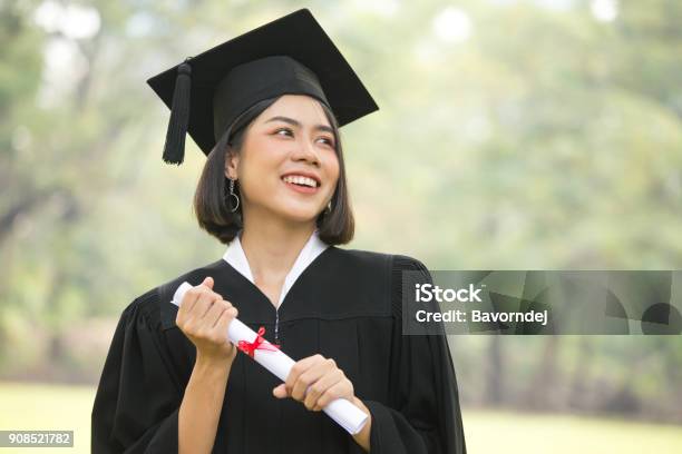 Young Asian Woman Students Wearing Graduation Hat And Gown Garden Background Woman With Graduation Concept Stock Photo - Download Image Now