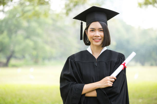 young asian woman students wearing graduation hat and gown, garden background, woman with graduation concept. - grad portrait imagens e fotografias de stock