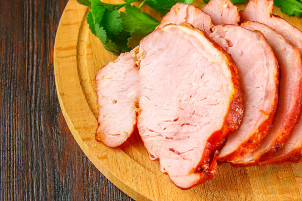 istock Sliced Roast Pork Loin on a brown wooden table with cilantro. 908528892