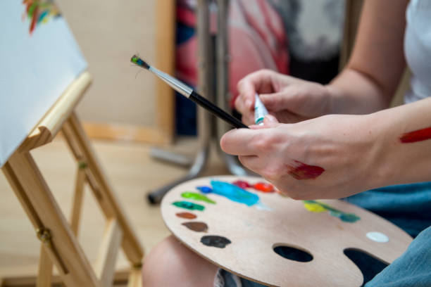istock Happy young woman paints on canvas 908529084