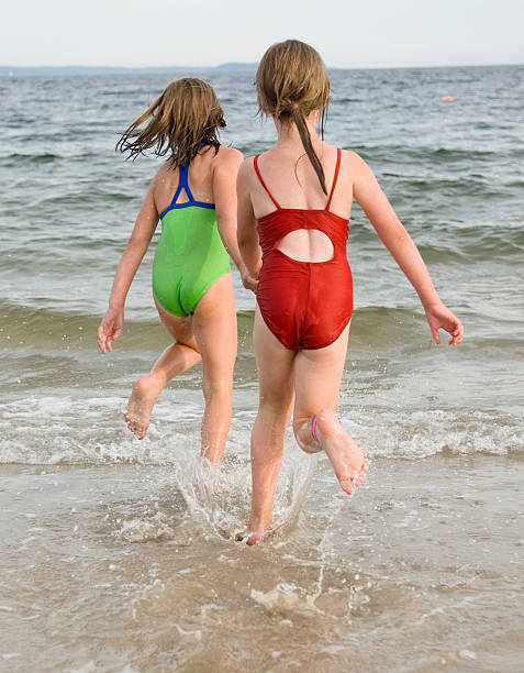 two young girls running into ocean stock photo