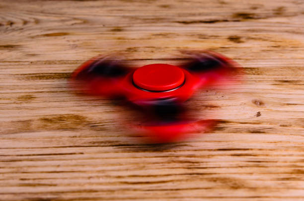 istock Red fidget spinner rotates on wooden desk 908538398
