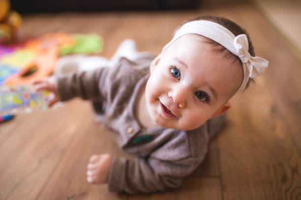 Cute Baby Girl Crawling In Living Room Adorable Baby Girl Learning How To Crawl At Her Warm Home baby girls stock pictures, royalty-free photos & images