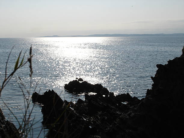 rocky coastline in glistering sun - fsachs78 stockfoto's en -beelden