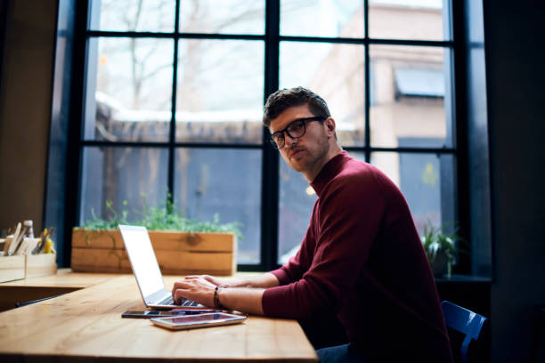 istock Handsome male skilled freelancer making distant job keyboarding text messages on laptop computer, young hipster guy in casual wear and glasses chatting with friends in social networks updating profile 908550144