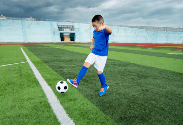 istock Young boy playing soccer ball on the field 908554408